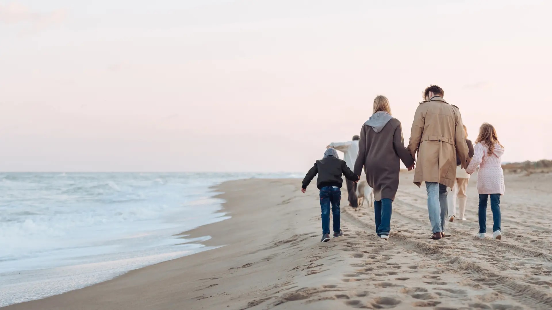Family walking on a sandy beach, symbolising health and wellbeing insurance for families