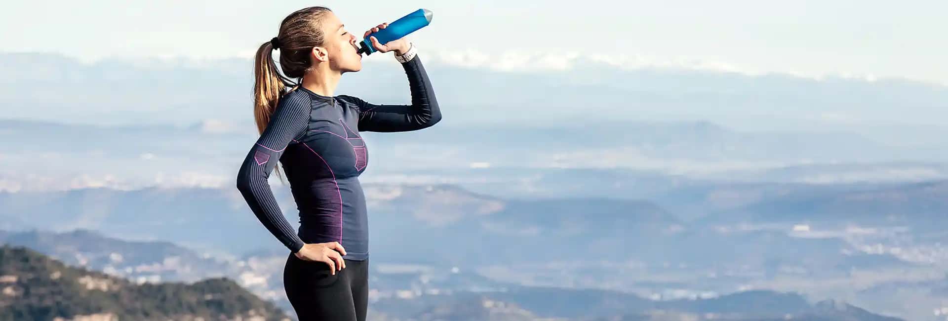 Runner drinking water with mountains on background