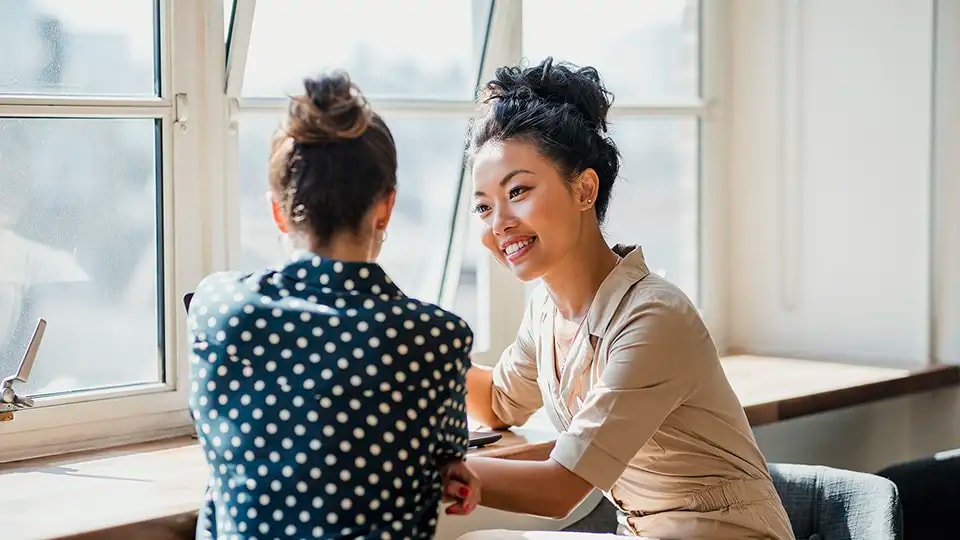 Two professional looking women talking at work