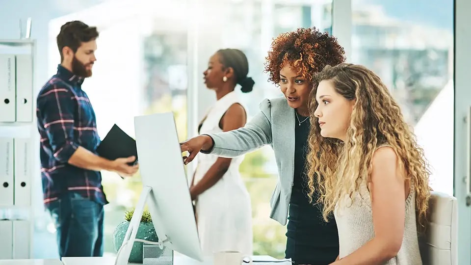 Two professional women looking at a computer monitor