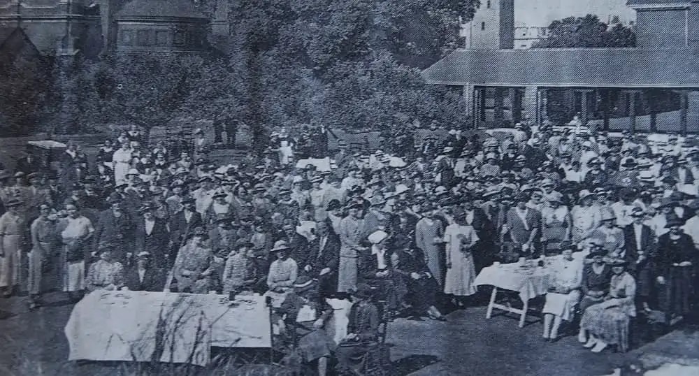 Group of people in 1900's sitting outside a building