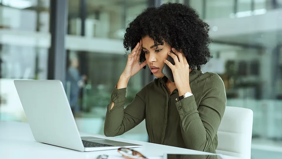 Woman looking overwhelmed by technology with her head in her hands