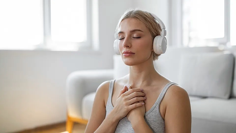 Woman looking focused as she meditates with headphones on