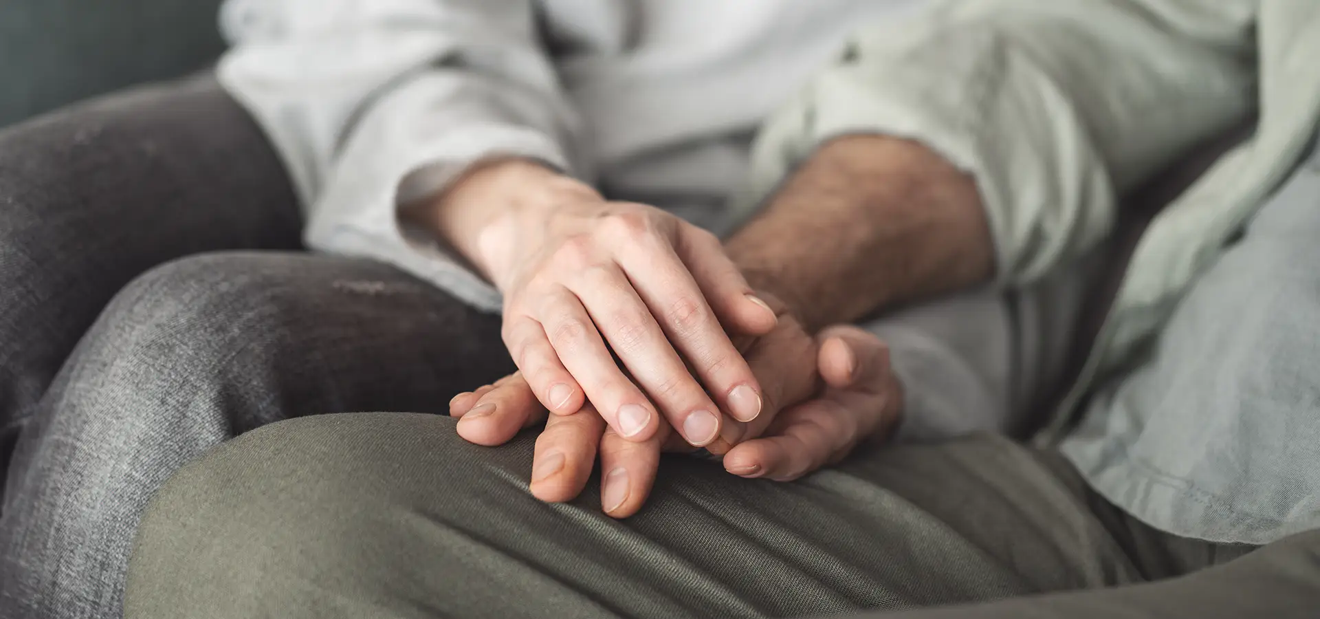 Two people saw down holding hands