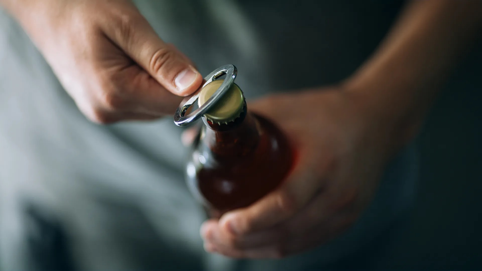 Close up of a man opening a bottle of beer
