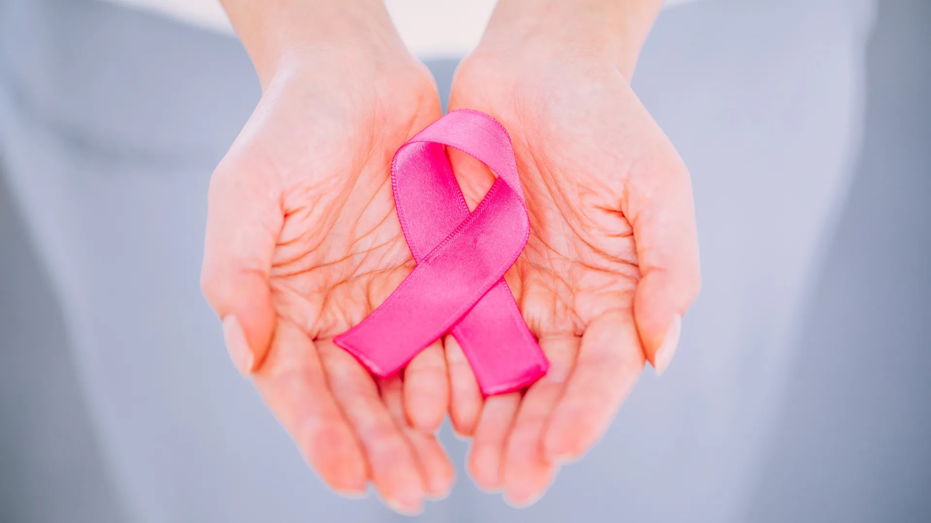 Woman hand holding pink ribbon breast cancer awareness